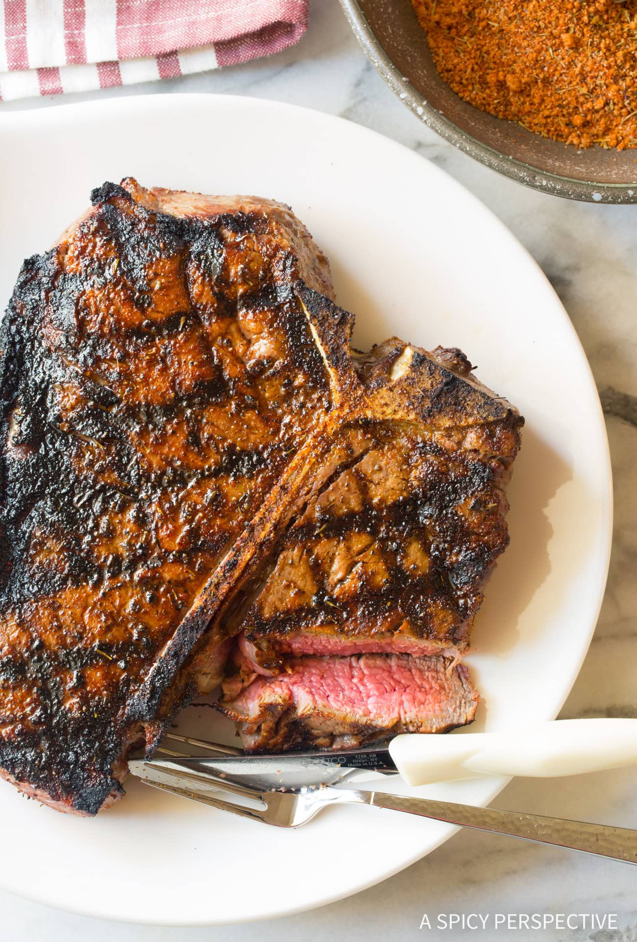 Overhead shot of steak on a white plate with fork and knife. 