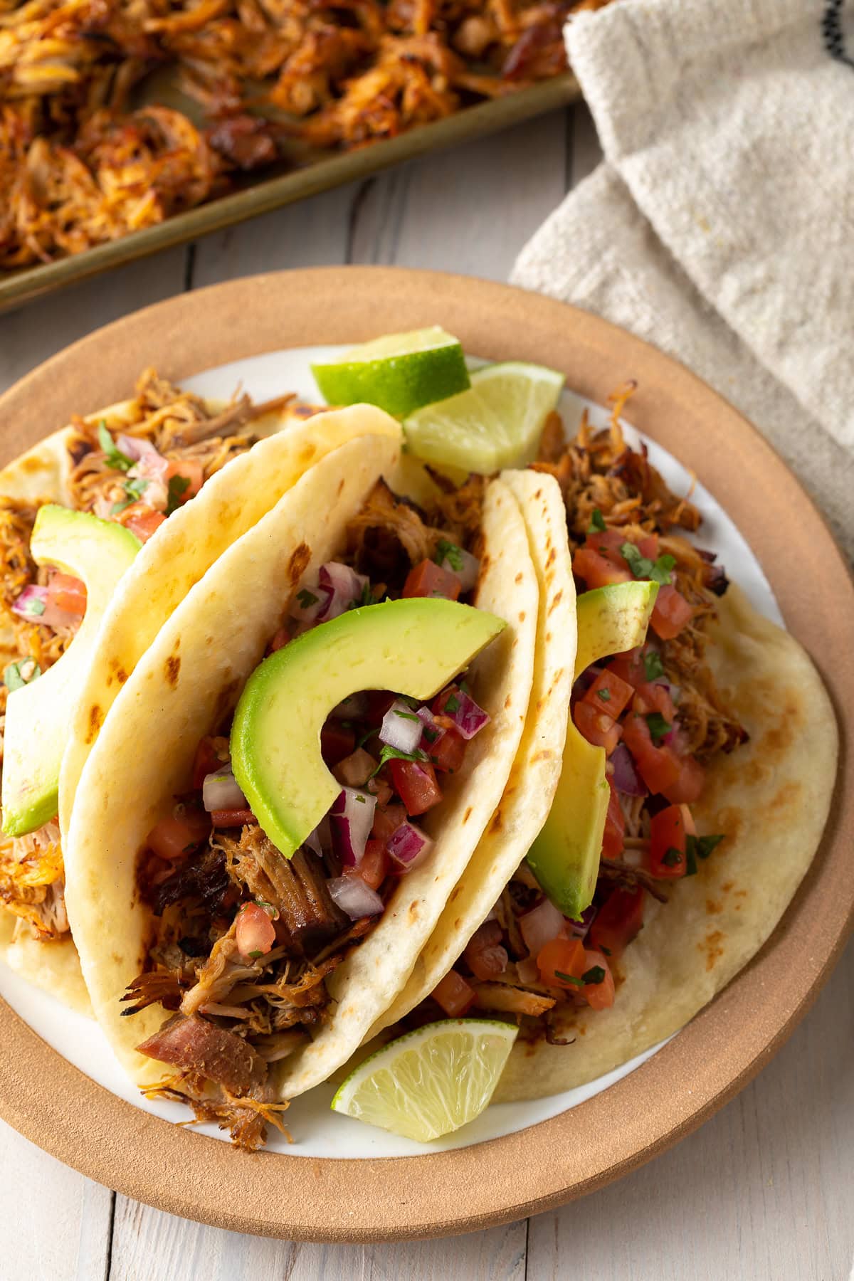 Carnitas tacos with toppings on a plate.