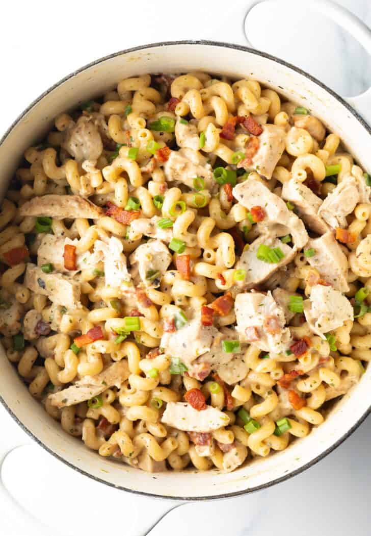 Top down view creamy pasta with chicken, bacon, and green onions.