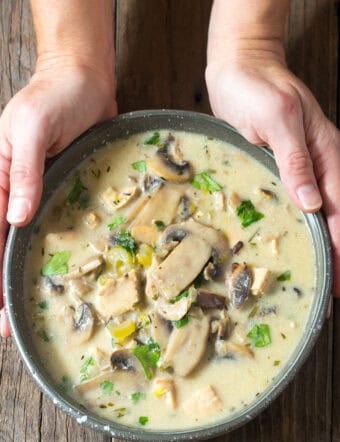 Creamy Chicken Mushroom Soup in bowl with hand holding the bowl