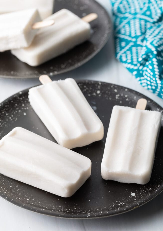 Three coconut milk popsicles on a plate.