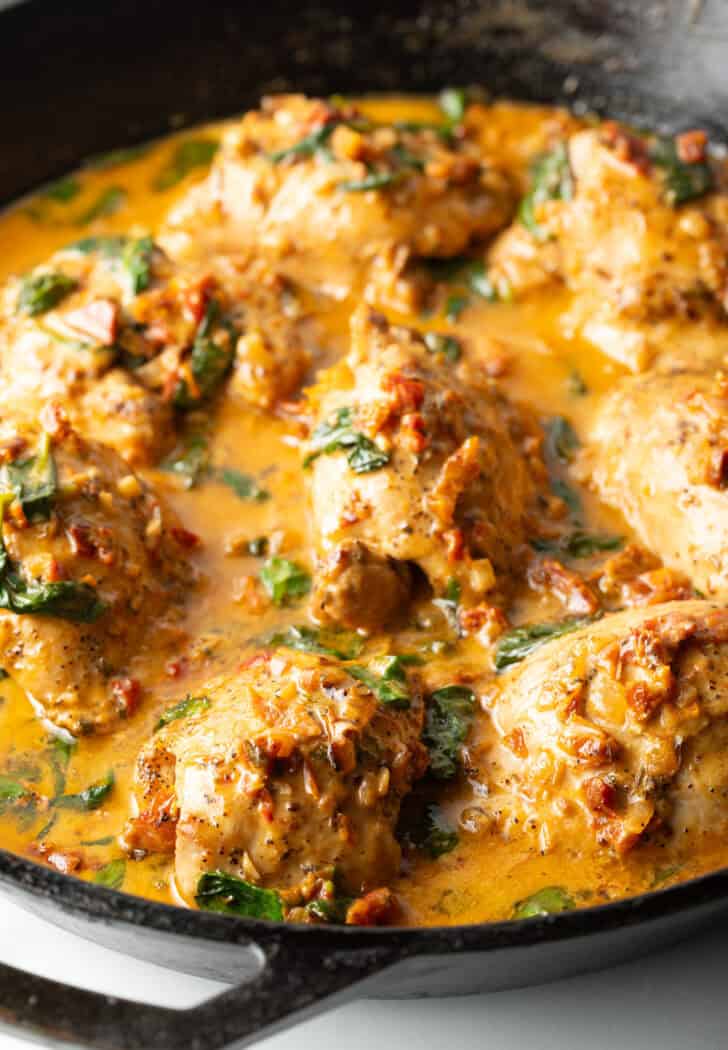 Creamy Tuscan chicken thighs in a skillet.