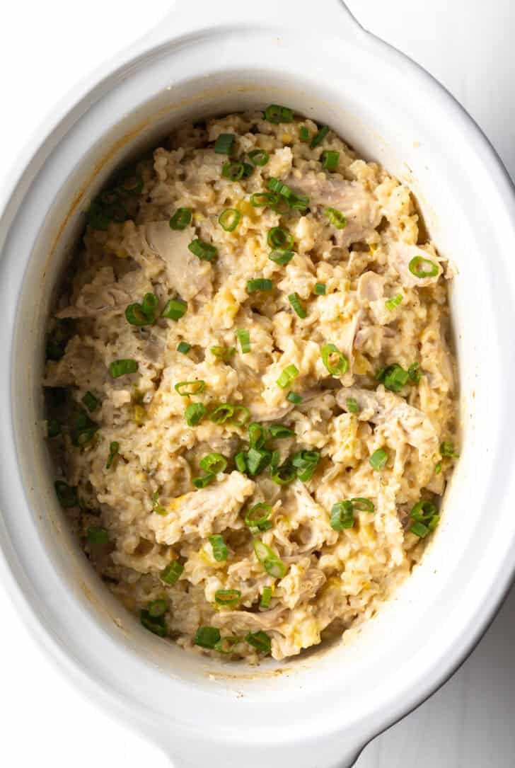 White crockpot with finished chicken and rice.