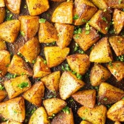 Top down view a rimmed baking sheet covered with chunks of crispy golden potatoes.
