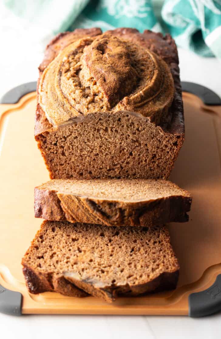 Loaf of healthy banana bread on a cutting board. Two front slices are layered.