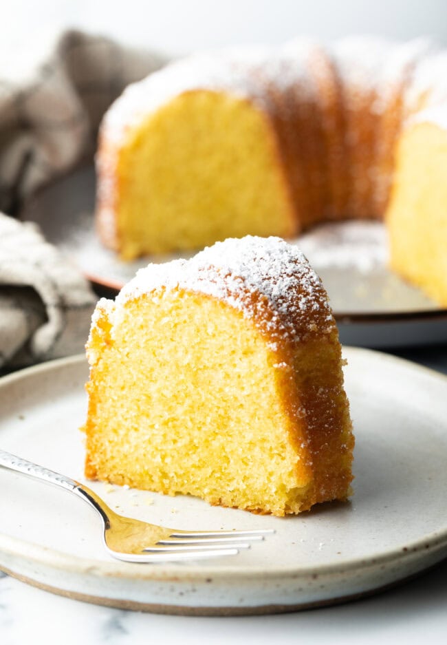Slice of yellow olive oil cake on a white plate.