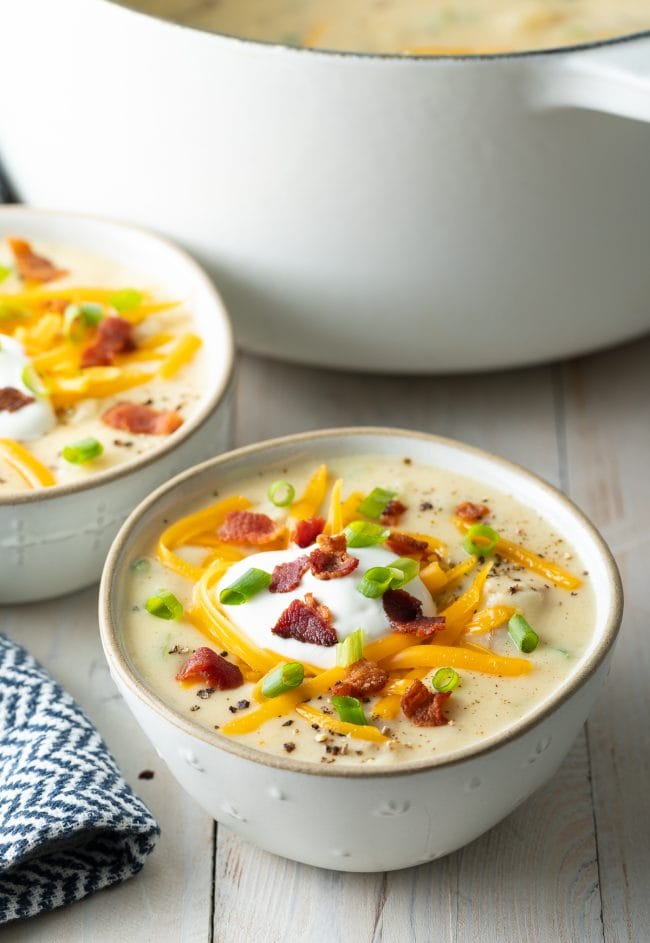 Bowl of easy potato soup topped with sour cream, cheese, bacon and scallions. 