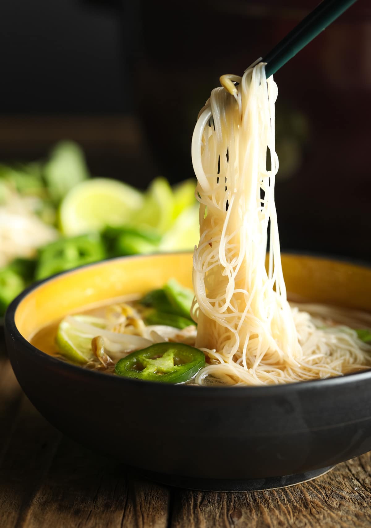 Healthy pho recipe in a bowl with chopsticks picking up lots of noodles.