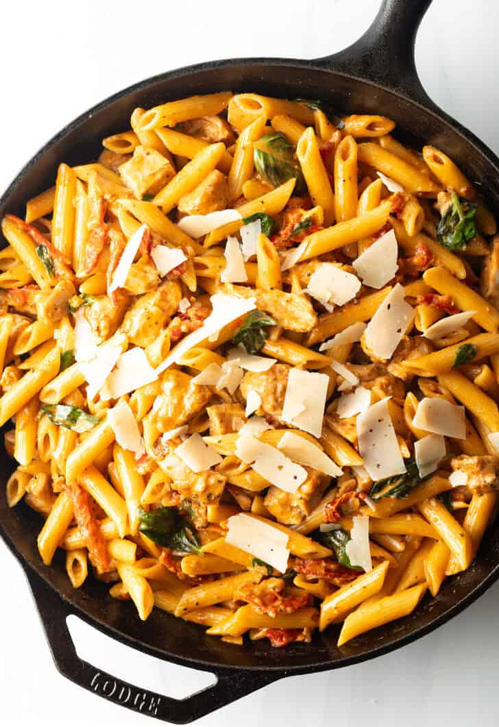 Cast iron skillet with pasta, chicken, and sun dried tomato sauce.