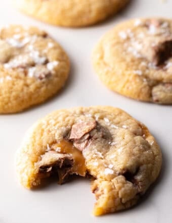 A Milky Way cookie on white surface with a bite taken out of it.