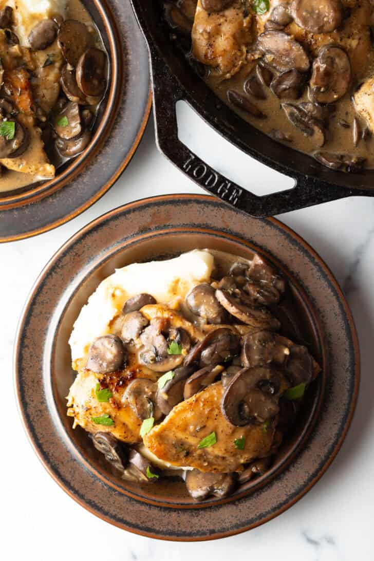 Top down view brown plate with mashed potatoes and. mushroom chicken.