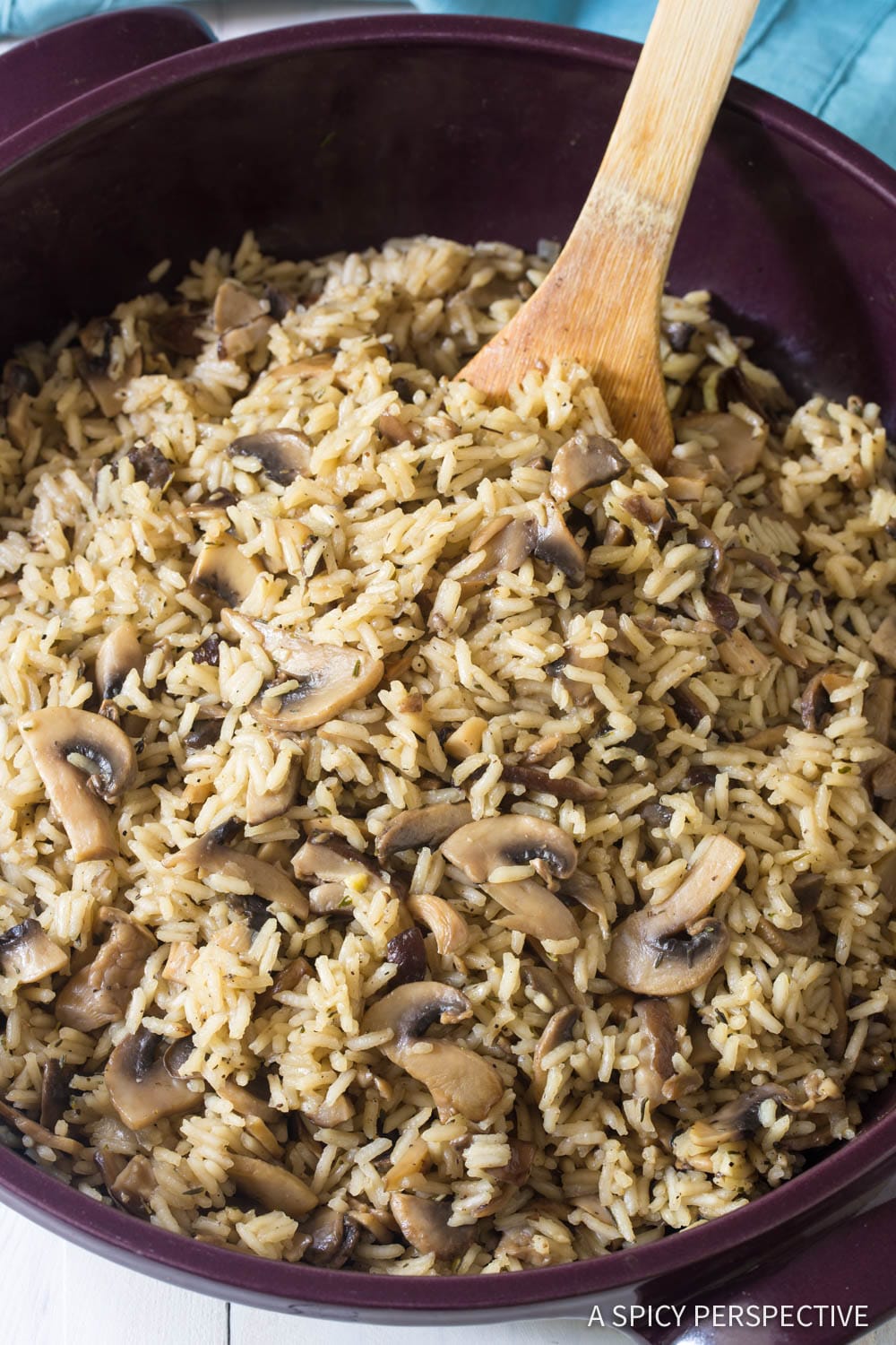 Mushroom rice recipe in a large pot with a wooden spoon. 