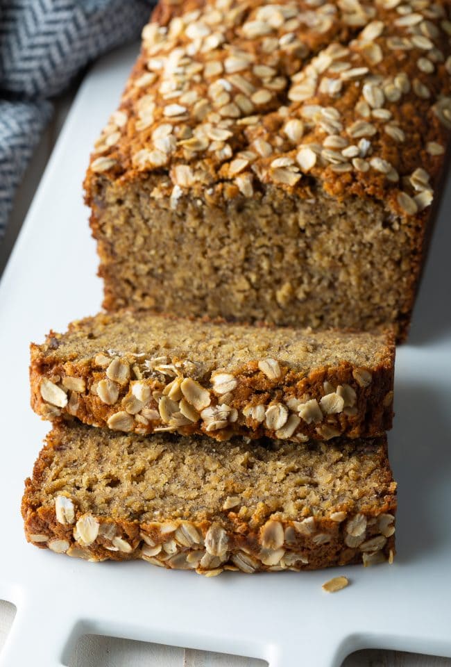 Banana oat bread on a plate with some slices off the end. 