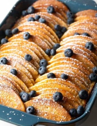 Pancakes lined up in a blue casserole dish for a make-ahead pancake breakfast casserole.