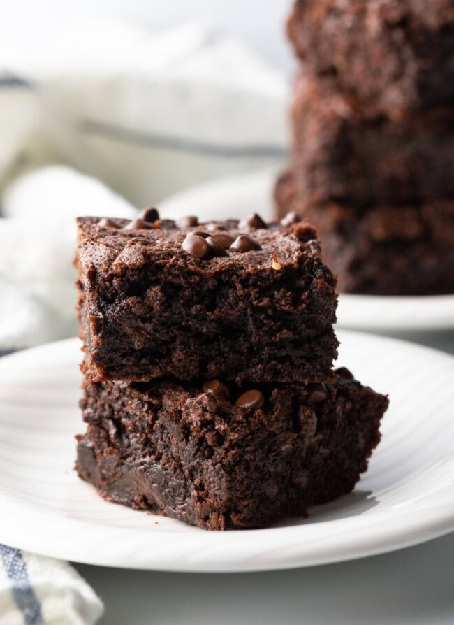 Two collagen protein brownies stacked on a white plate.