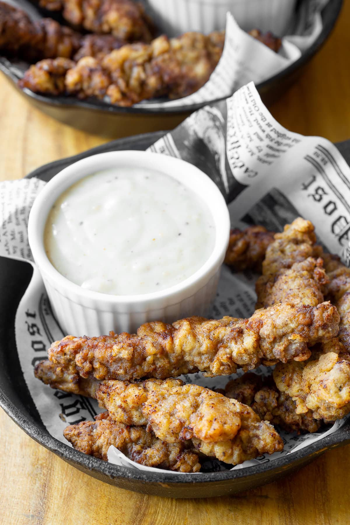 steak fingers recipe in a cast iron plate next to a saucer of gravy.