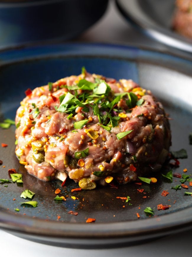 Plated steak tartare topped with fresh herbs. 