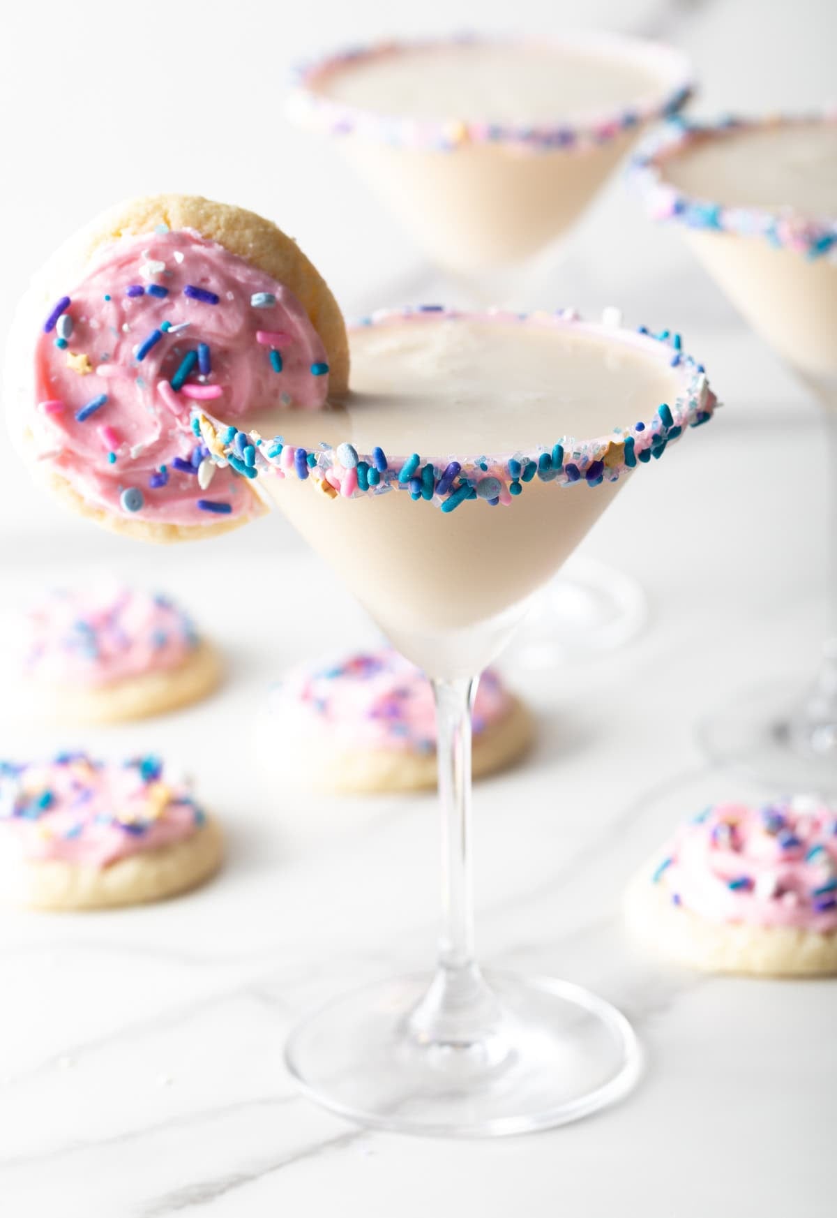 Colorful sugar cookie martini with a cookie on the rim surrounded by iced sugar cookies.