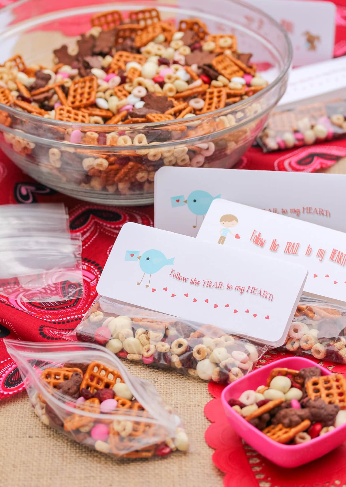 valentines day snacks (trail mix) in individual baggies with a bowl of trail mix in the background.